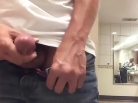 Solo boy masturbates with a large load on his face in a public restroom.